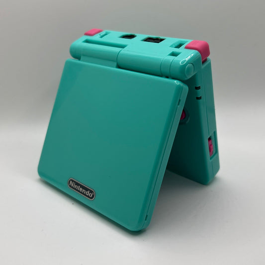 Teal Nintendo Game Boy Advance SP with pink buttons on a white background
