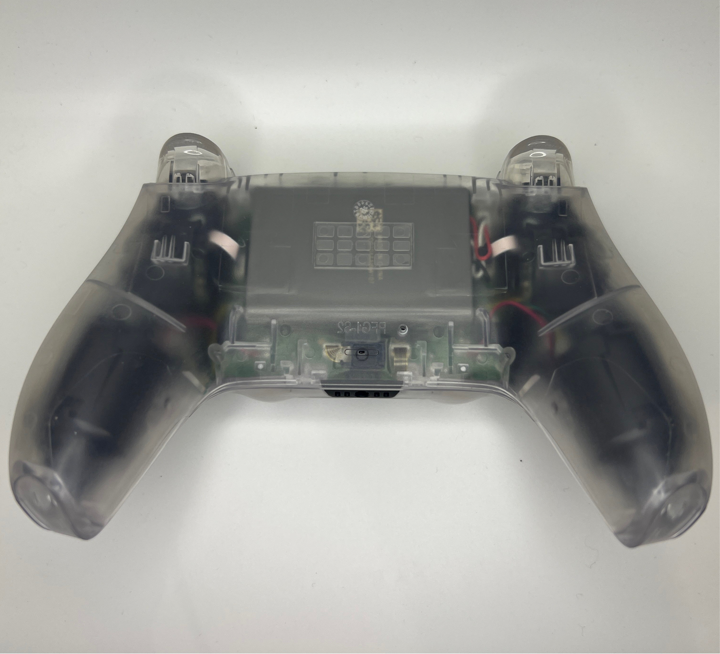 Close-up of a transparent PS5 controller with visible circuitry on a white background