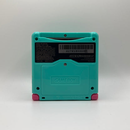 Teal Game Boy Advance SP with pink buttons on a white background
