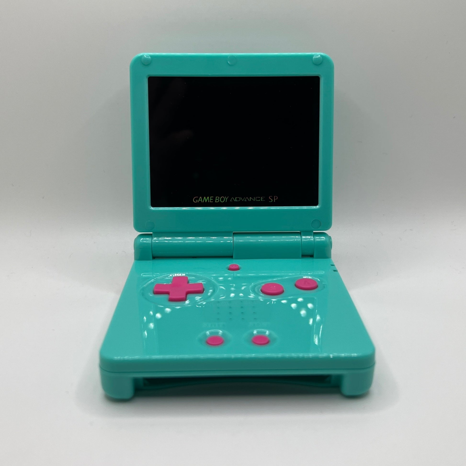 Teal Game Boy Advance SP with pink buttons on a white background